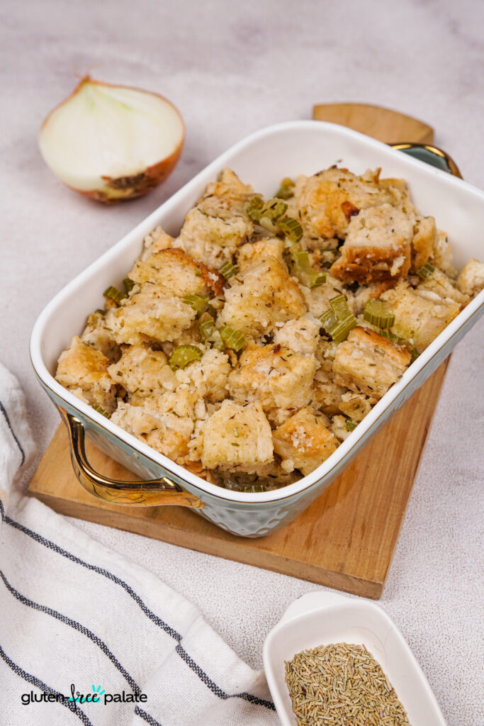 Gluten-free stuffing in a white serving dish on a wooden cutting board.