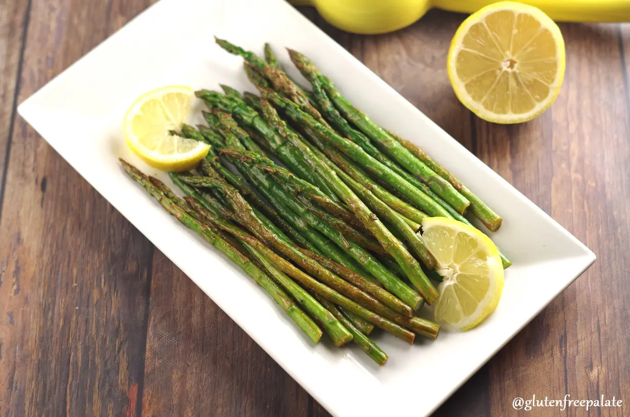 Asparagus spears on a white plate with slices of lemon