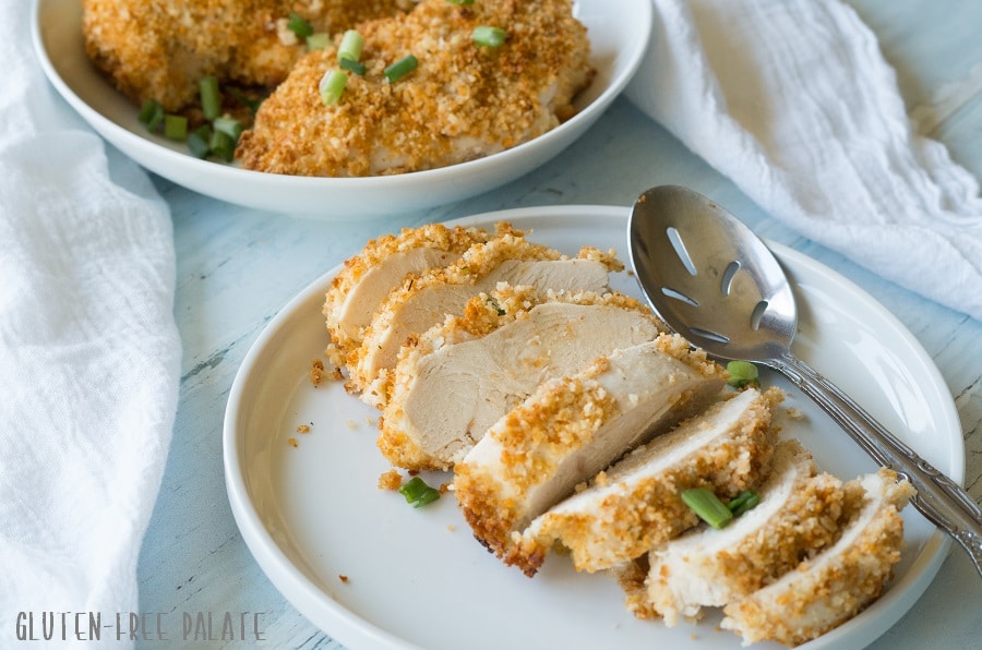 a side view of sliced breaded chicken on a white plate with a spoon