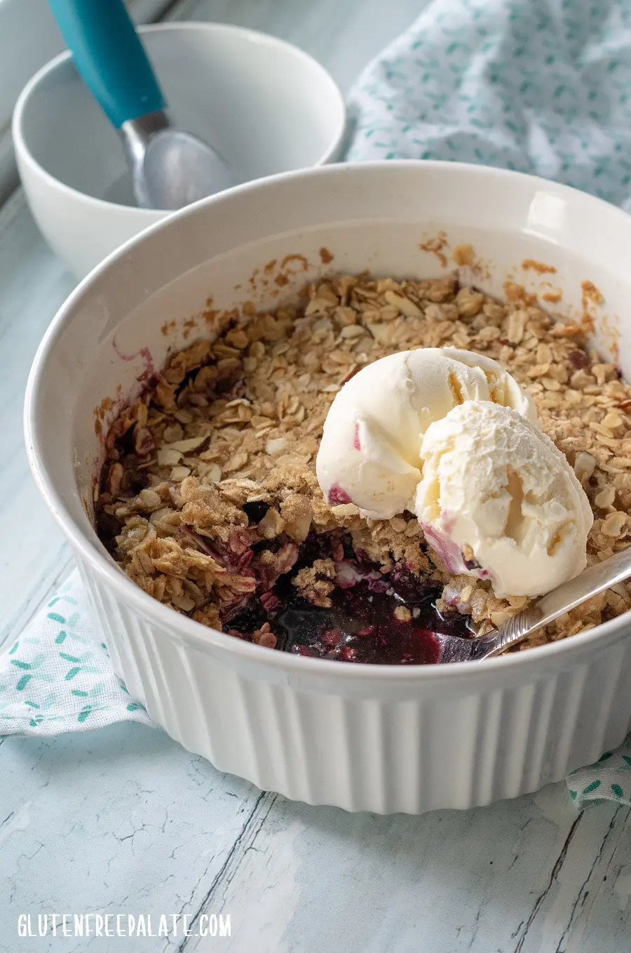 side view of blackberry crisp in a white dish with a spoon