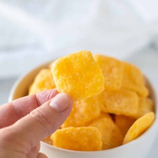 a hand holding a gluten-free cheese crackers