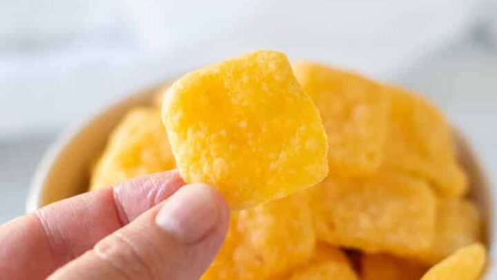a hand holding a gluten-free cheese crackers