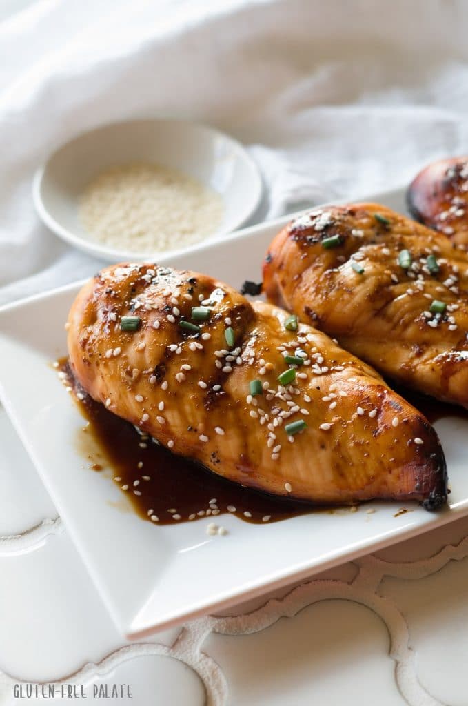a side view of three Hawaiian chicken breasts on a white plate with sauce