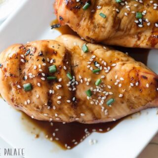 a close up a chicken bread on a white plate topped with seaseme seeds