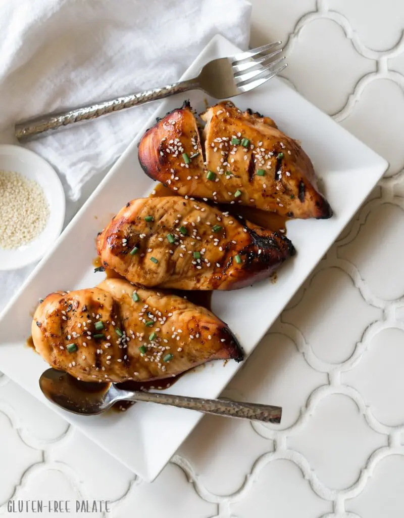 three Hawaiian chicken breasts on a white plate with sauce