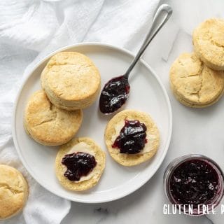 Three Gluten-Free Southern Biscuits on a white plate with butter and grape jam