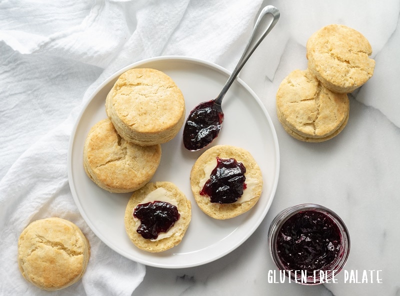 Three Gluten-Free Southern Biscuits on a white plate with butter and grape jam