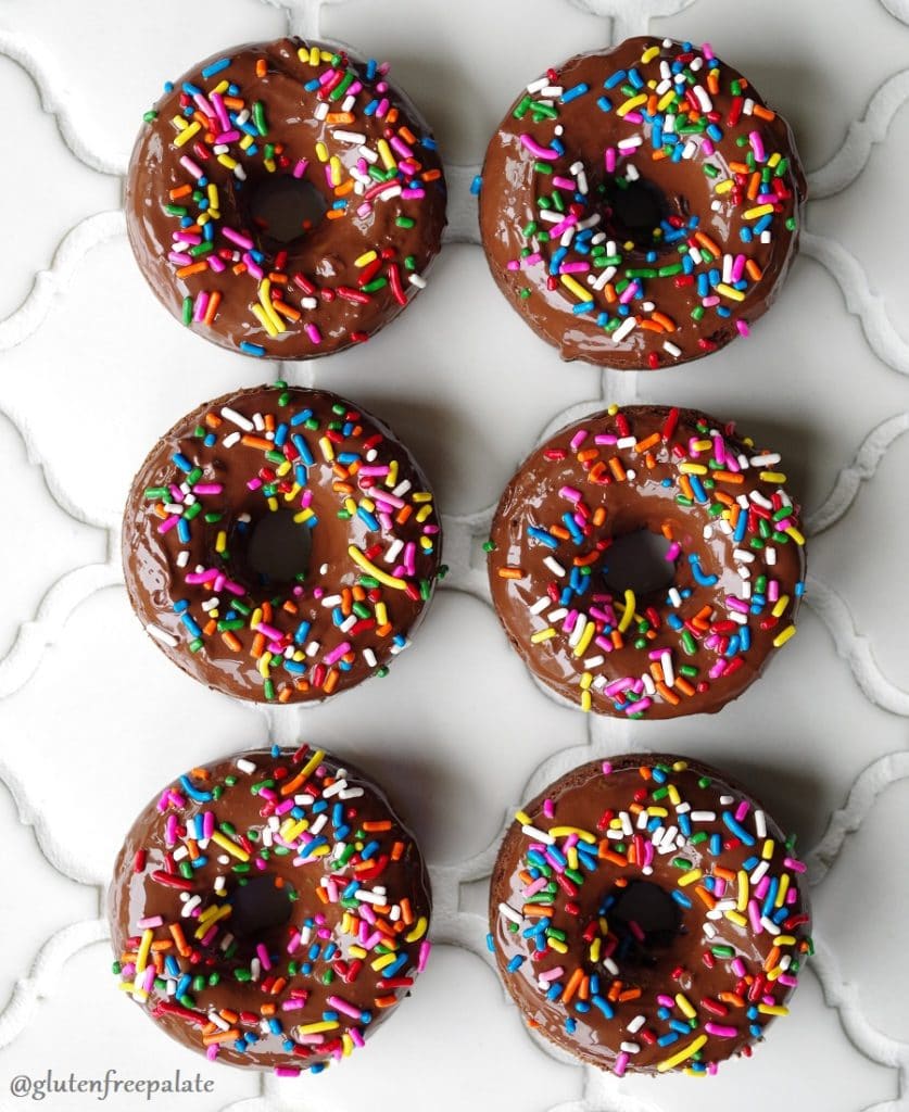 six chocolate cake donuts with chocolate glaze and colored sprinkels on top
