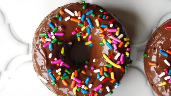 a close up of a chocolate donut with colored sprinkles