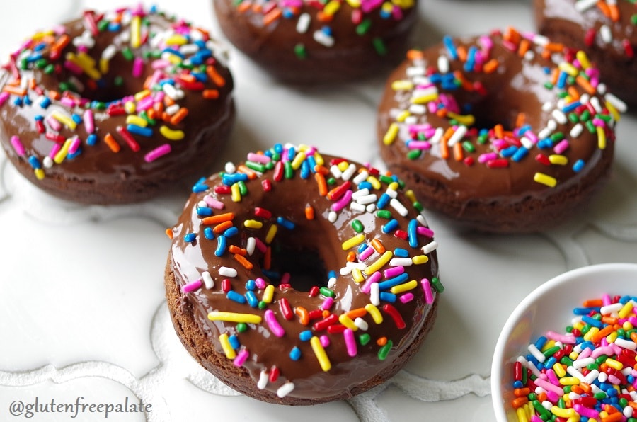 a side view of a close up of chocolate donuts with colored sprinkles