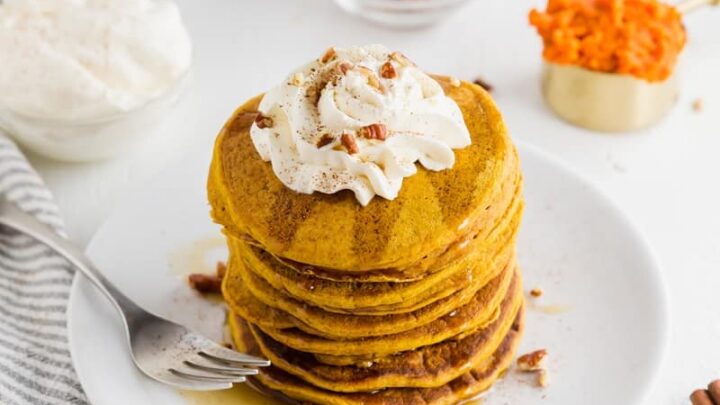 a stack of gluten free pumpkin pancakes topped with whipped cream