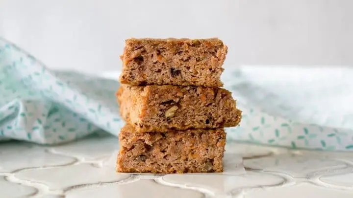 three Grain-Free Carrot Cake Bars stacked on a white counter