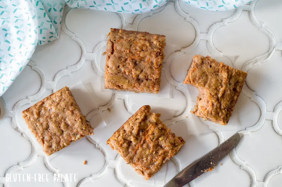 a top down view of four paleo carrot cake bars, one has a bite taken out