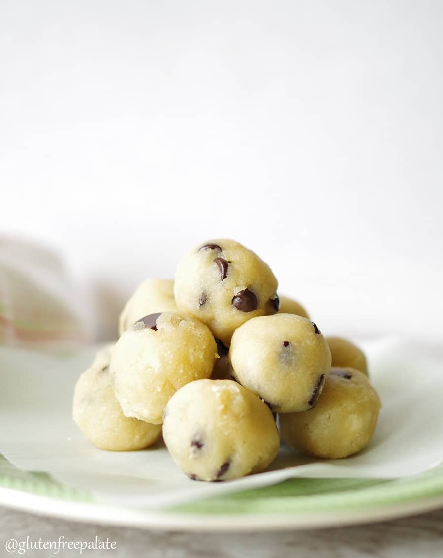 a close up of gluten free cookie dough bites stacked on a plate