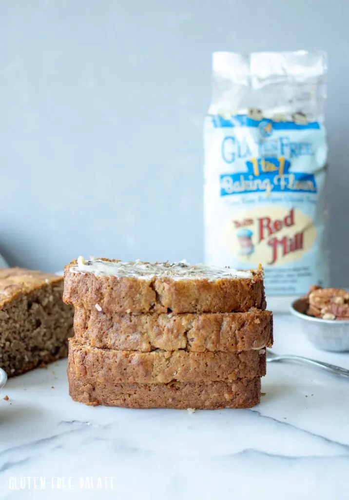 four slices of Banana Bread sliced on a plate with a bag of flour in the background