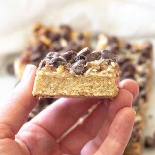 a close up of a hand holding a seven layer bar