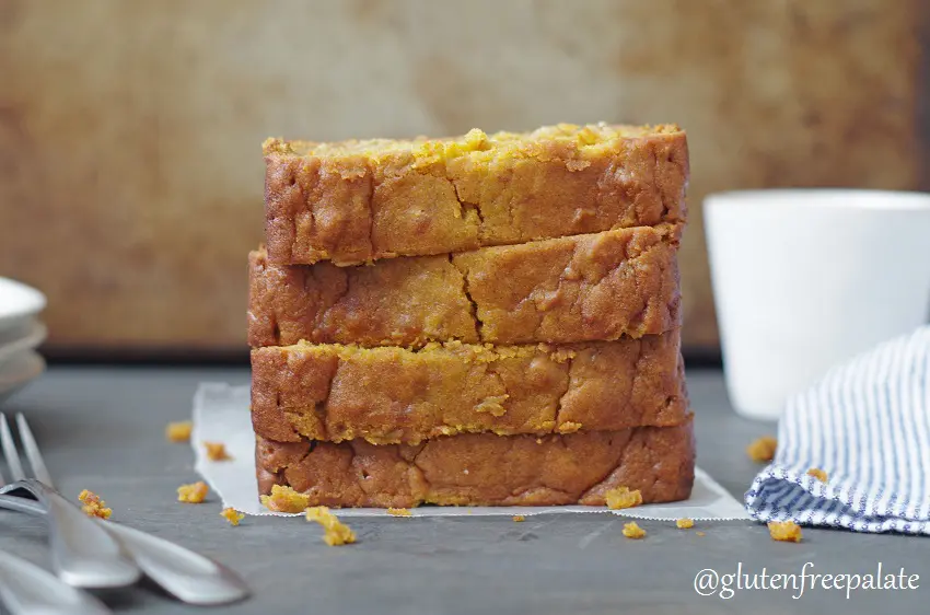four slices of gluten-free pumpkin bread stacked, next to forks and a stripe napkin
