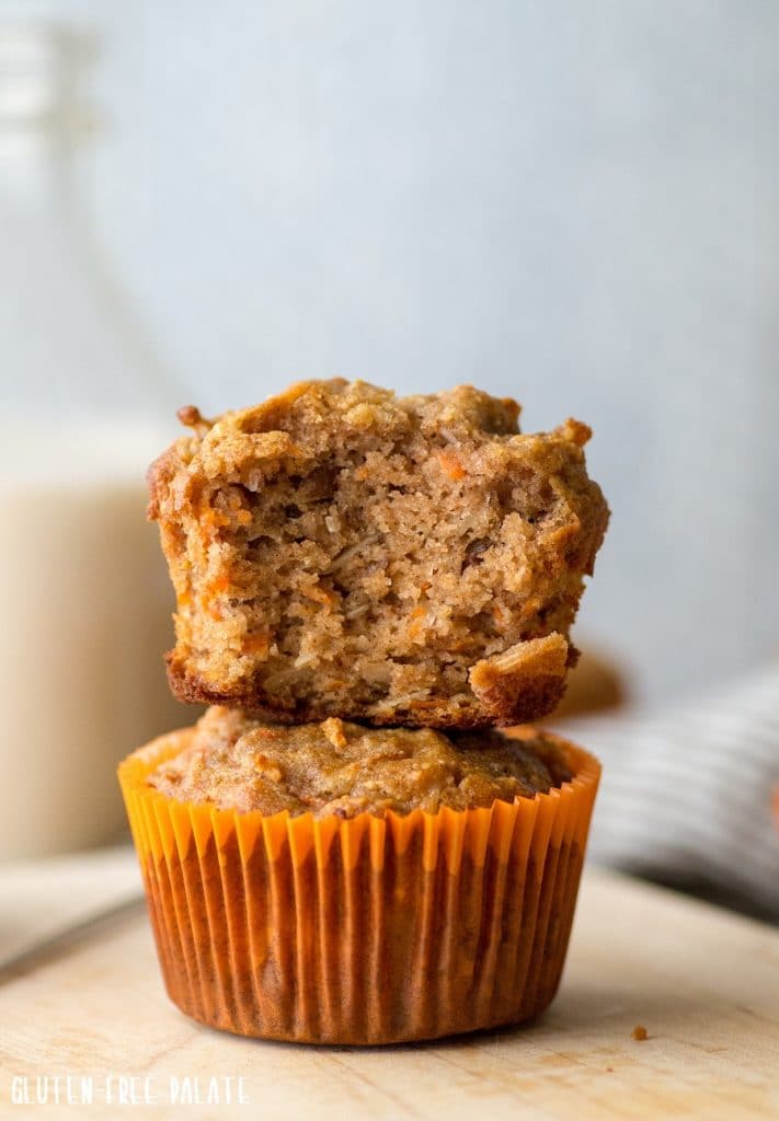 A paleo carrot cake muffin with a bite out stacked on another paleo muffin