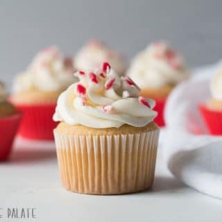 a close up of a cupcake topped with white frosting and candy cane pieces
