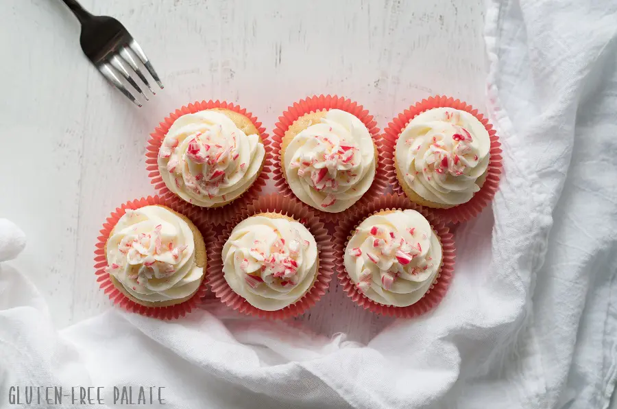 a top down view of six gluten free peppermint cupcakes topped with white frosting and candy cane pieces