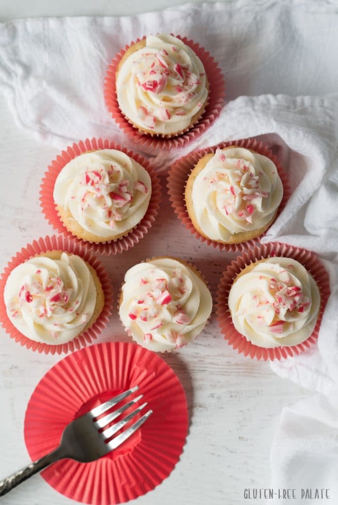 a top down view of six cupcakes topped with white frosting and candy cane pieces