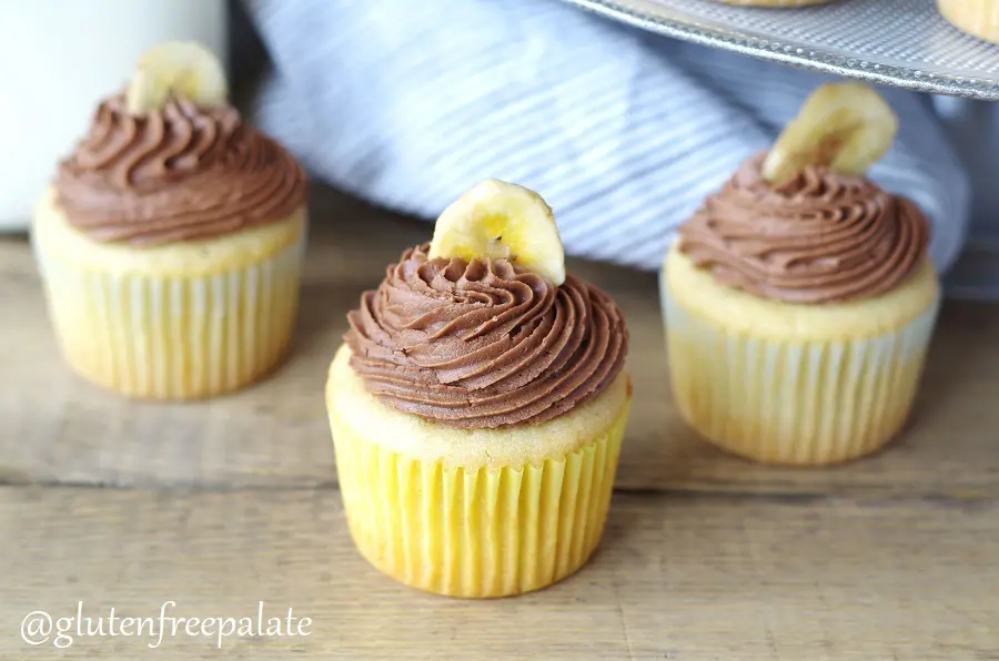 three banana cupcakes topped with chocolate frosting and a banana chip