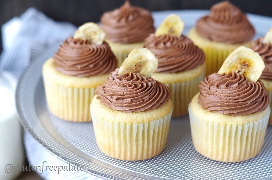 a close up of banana cupcakes topped with chocolate frosting and a banana chip