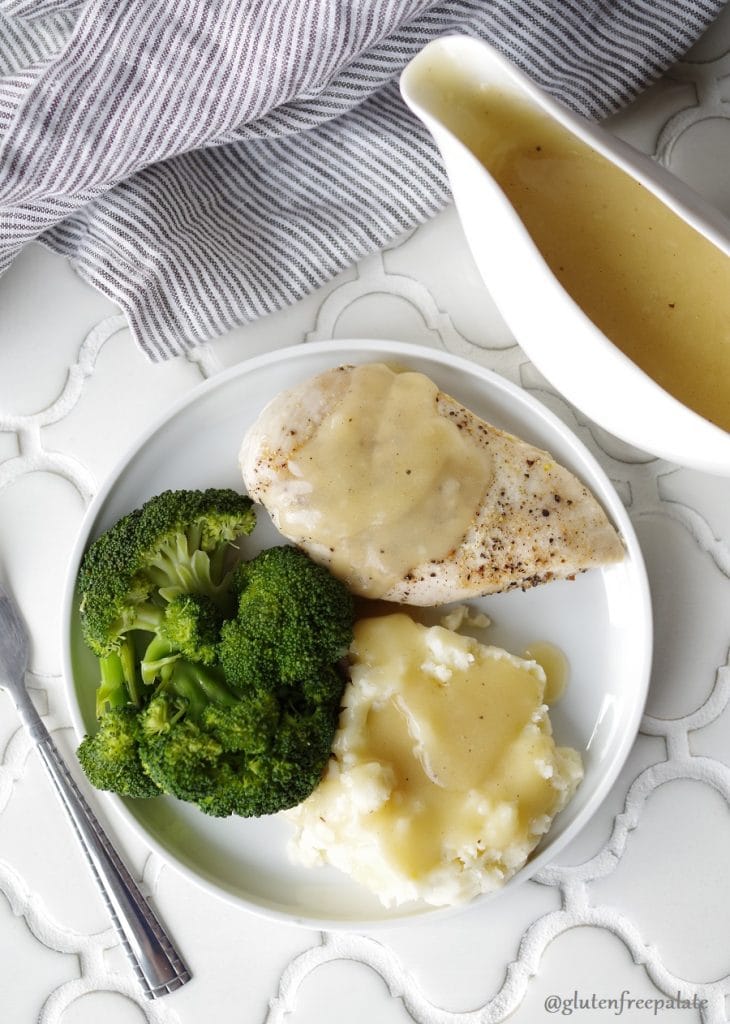 chicken and mashed potatoes with gravy on a white plate with broccoli