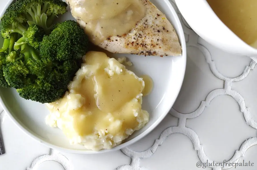 a close up of chicken and mashed potatoes with gluten free gravy on a white plate with broccoli