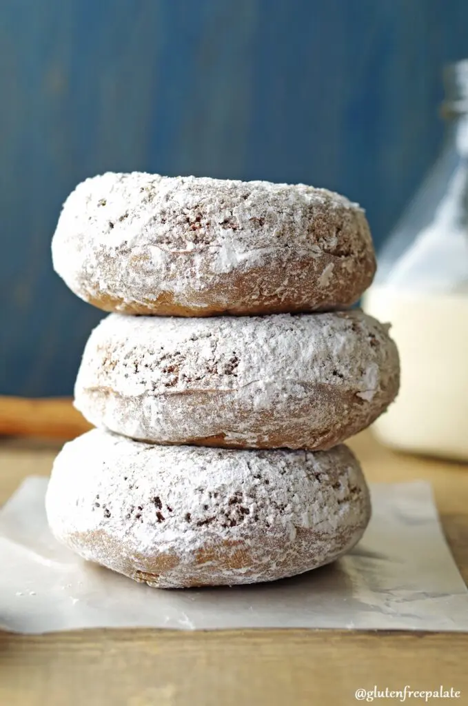 three gingerbread donuts coated in powdered sugar stacked