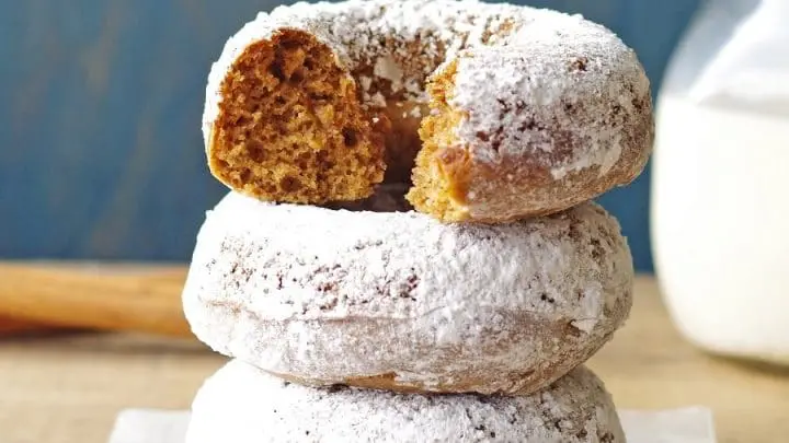 three Gluten-Free Gingerbread Donuts covered in powdered sugar and stacked