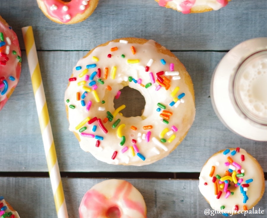 a close up of a vanilla cake donut with white icing and colored sprinkles