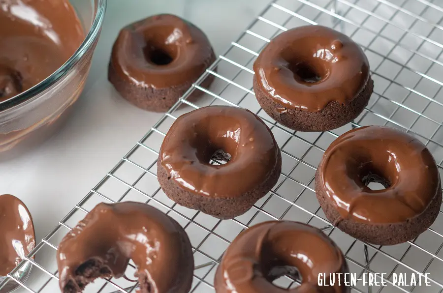 gluten free vegan chocolate donuts on a wire cooling rack topped with melted chocolate