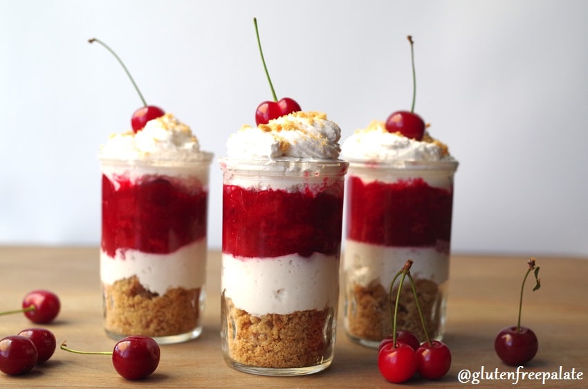 three shot glasses filled with layers of graham cracker crumbs, whipped cream, cherry pie filling