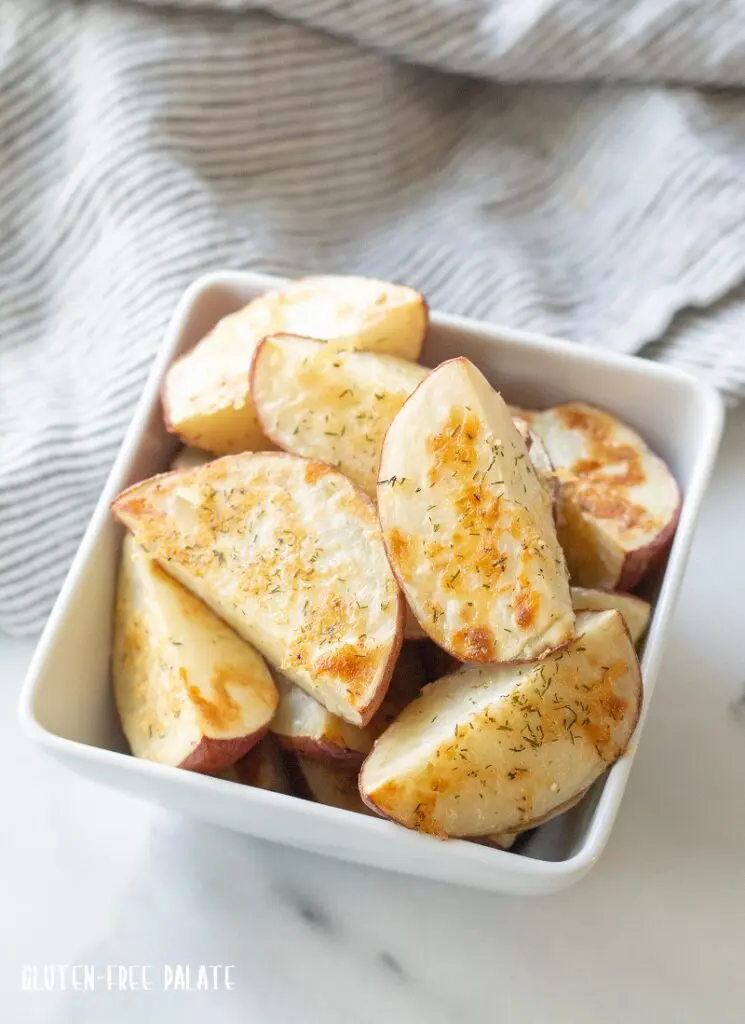 a side view of cooked Red Roasted Potatoes in a white bowl with a striped napkin.