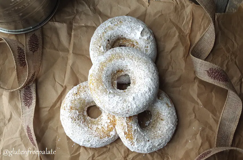 top down view of gluten-free pumpkin donuts stacked on a brown bag