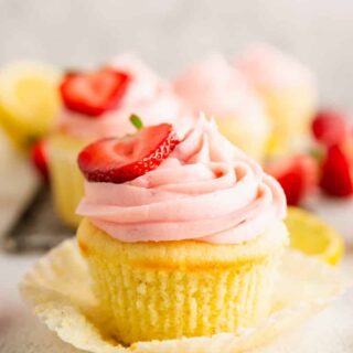 a lemon cupcake with strawberry frosting with a strawberry half on top