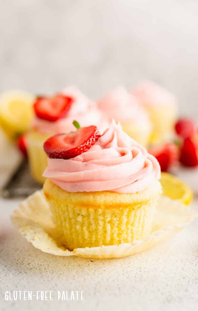 a lemon cupcake with strawberry frosting with a strawberry half on top