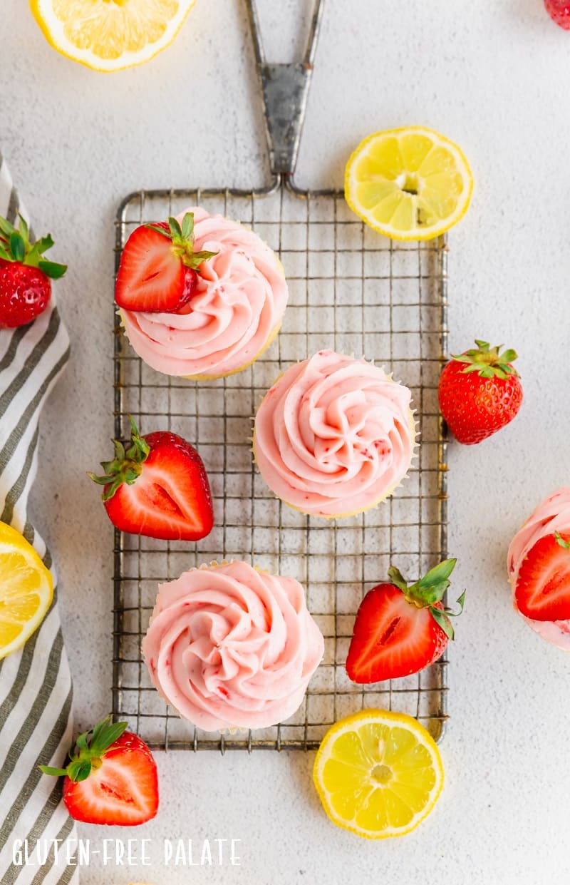 top down view of three gluten free strawberry cupcakes next to strawberry halves