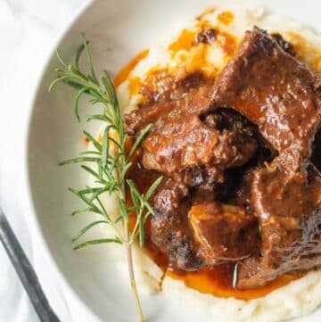 A close up top down view of beef short ribs over mashed potatoes