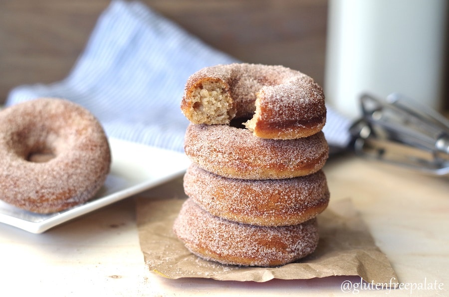 four stacked cinnamon sugar donuts, the top donut has a bite out
