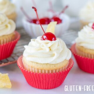 a close up of Gluten Free Pina Colada Cupcakes with a cherry on top