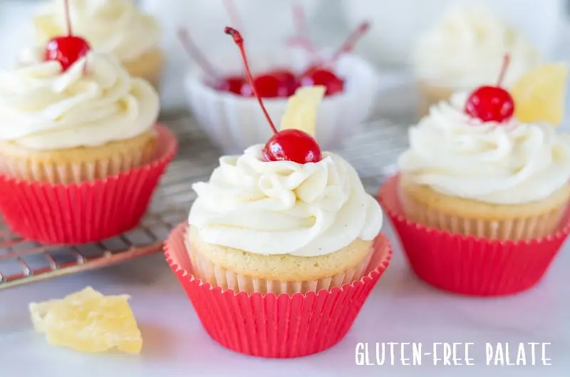 Gluten Free Pina Colada Cupcakes with a cherry on top with dried pineapple