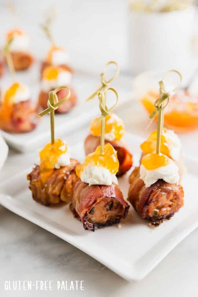 Five sausage appetizers on a white plate.