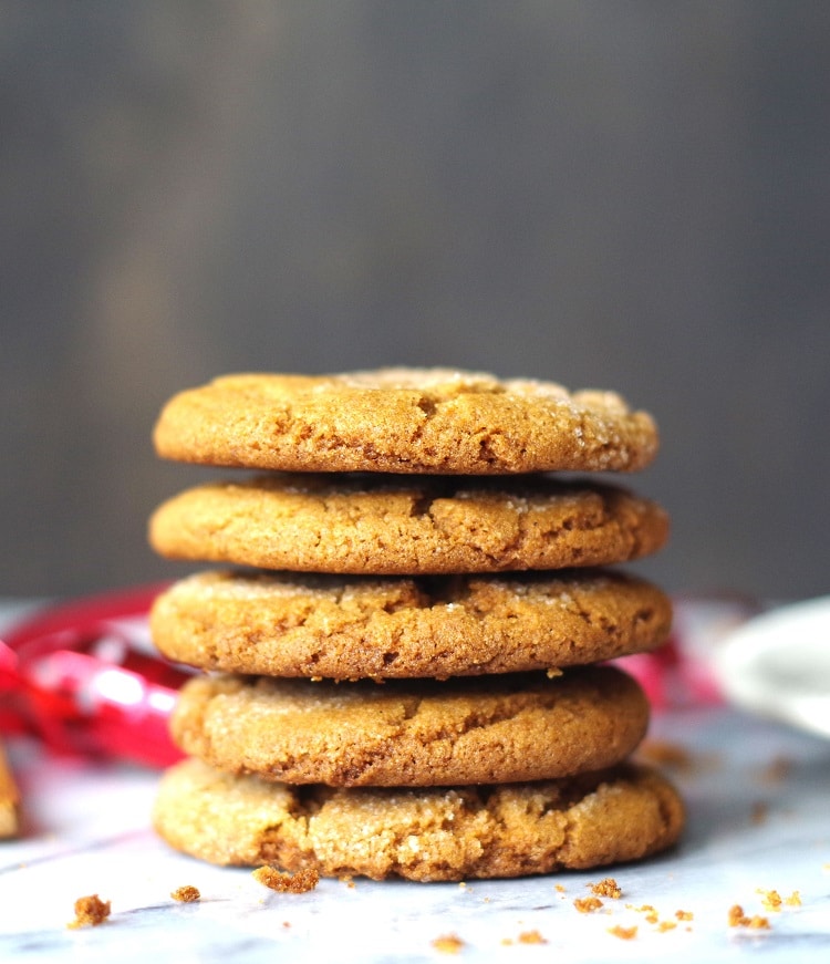 five ginger snap cookies stacked with red ribbon on marble
