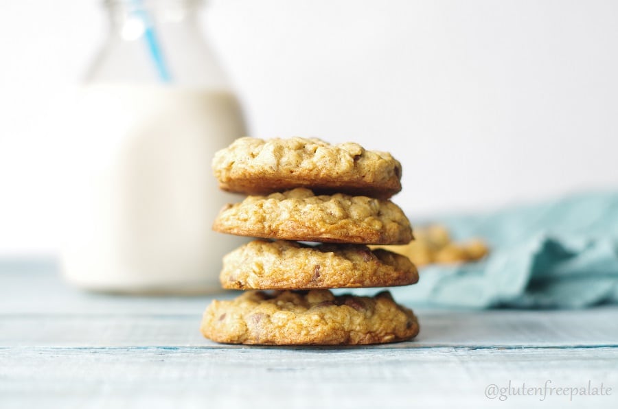 four oatmeal cookies stacked in front of a jar of milk