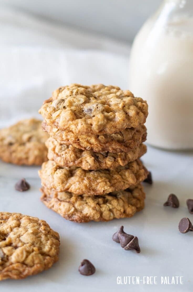 five gluten free oatmeal cookies stacked with chocolate chips scattered around them