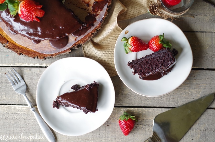 slices of Gluten-Free Vegan Chocolate Ganache Cake on white plates, one served with strawberries
