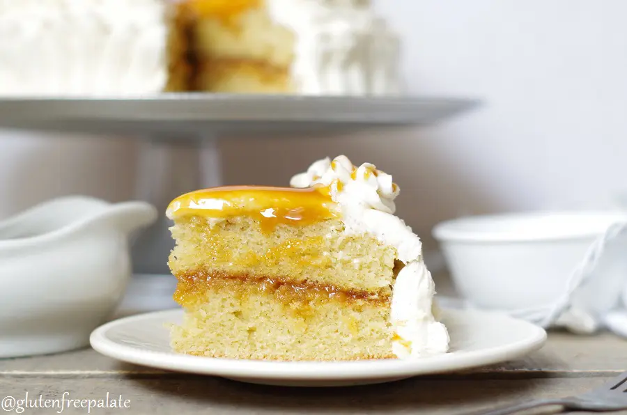 a slice of gluten free caramel cake topped with frosting and caramel on a white plate