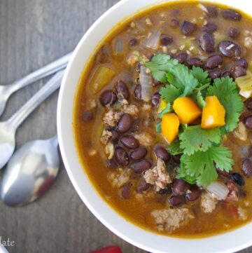 A close up top view of spicy black bean soup topped with cilantro